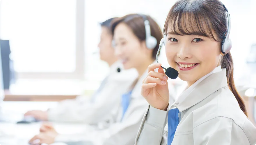 作業着を着た電話受付の女性が笑っています