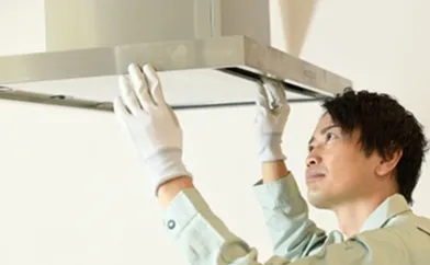 作業服を着た男性と換気扇